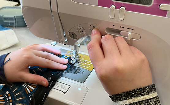 mains enfants qui utilisent une machine à coudre avec du tissu polyèdre seynod annecy