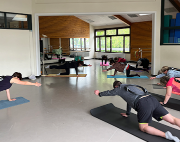 personnes sur tapis en position pilates avec bras en l'air polyèdre seynod annecy
