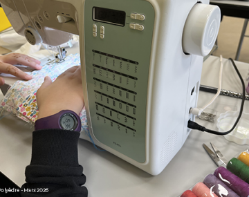 mains fille qui utilise une machine à coudre avec bobines de fils colorés à droite polyèdre seynod annecy