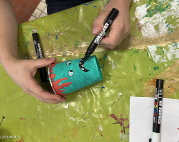 mains de garçons qui colorie et dessine sur un gobelet en carton polyèdre seynod annecy